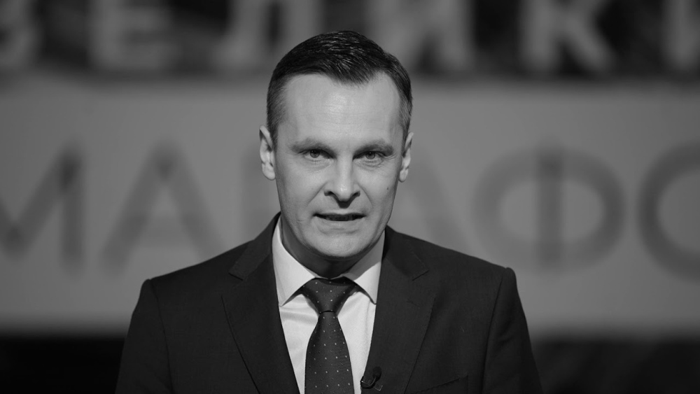 Чоловік у темному костюмі та краватці перед камерою